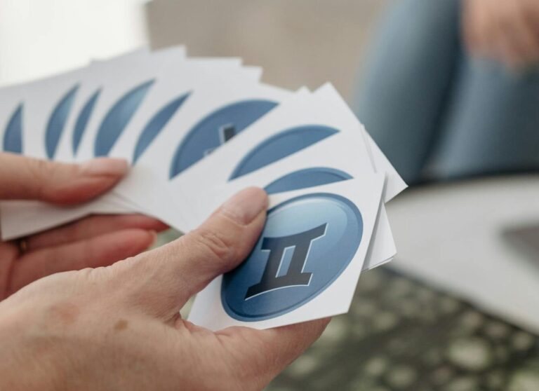 A person holding Gemini cards during a tarot reading session indoors, suggesting astrology and mystery.
