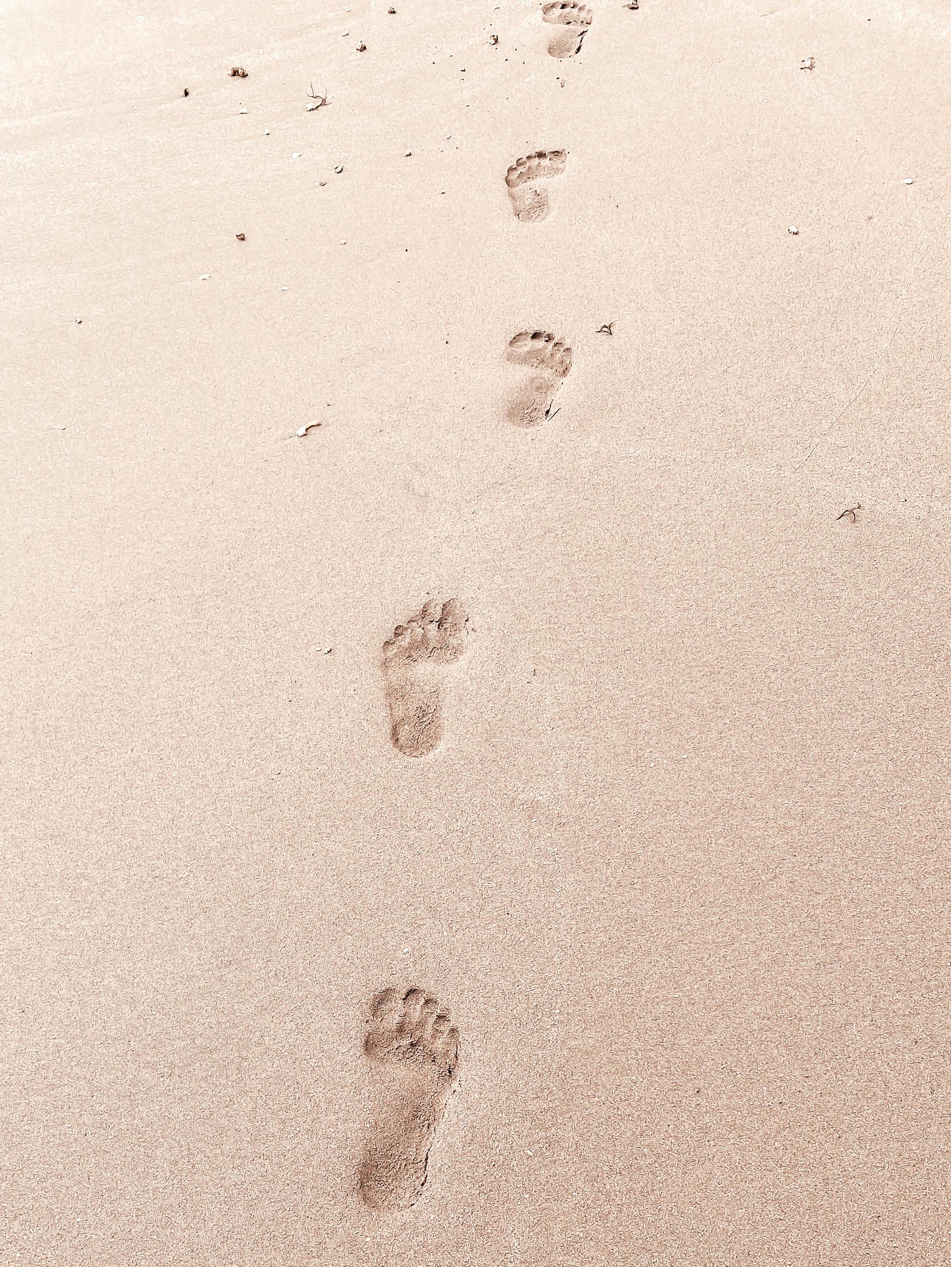 A series of footprints leading away on a sandy beach in Banten, Indonesia.