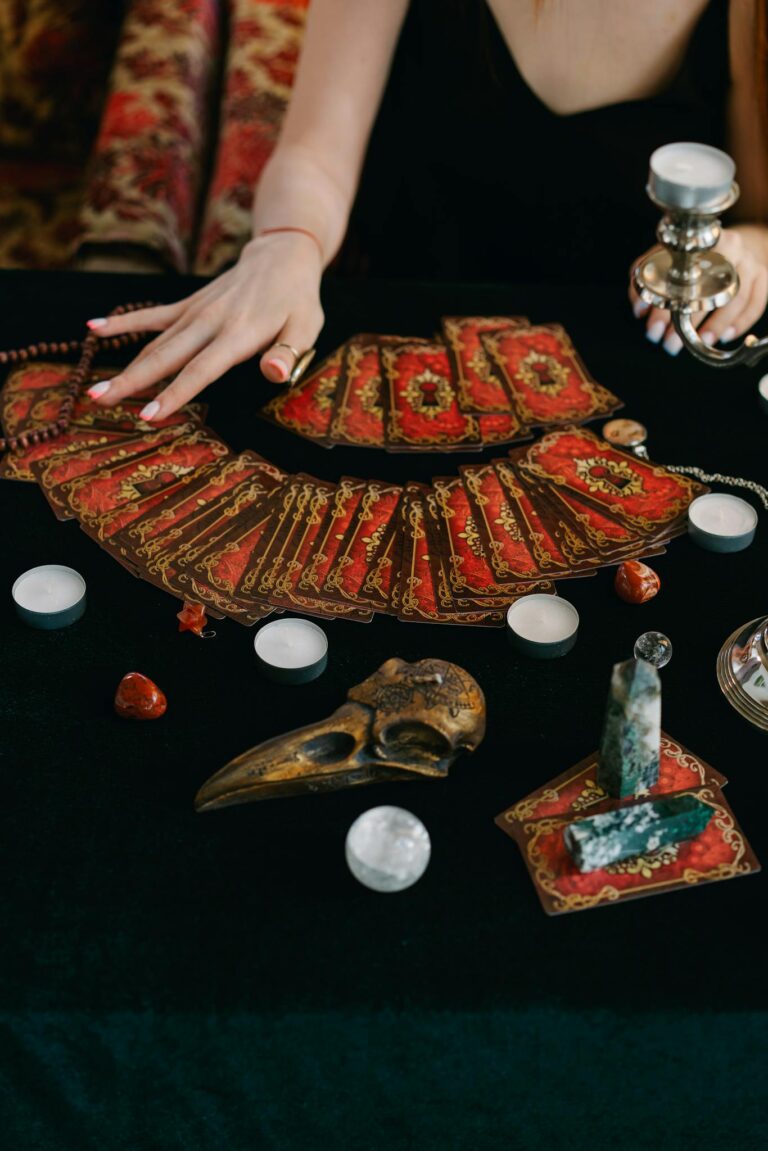 An ornate tarot card spread with crystals and candles on a black table, evoking a mystical atmosphere.