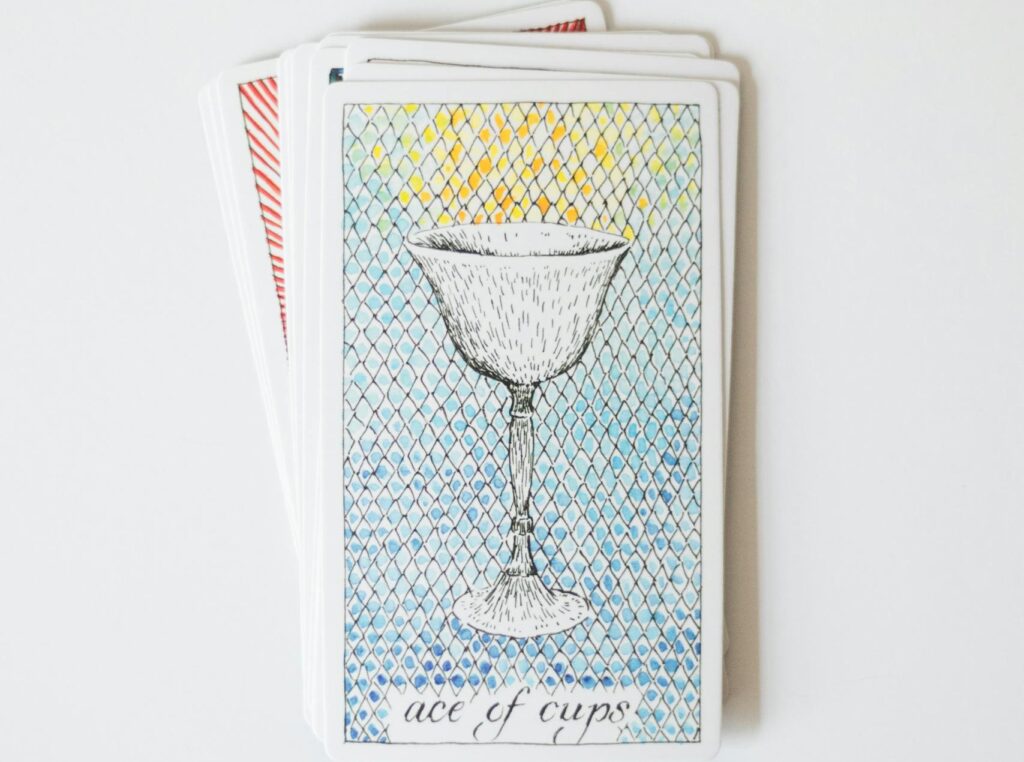 Top view of Ace of Cups tarot card against a minimalistic white background.